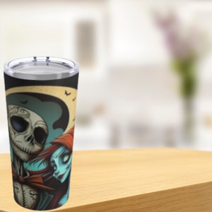May include: A stainless steel tumbler with a black and white image of Jack Skellington and Sally from the Nightmare Before Christmas movie. The image shows them embracing under a crescent moon with bats flying in the background.