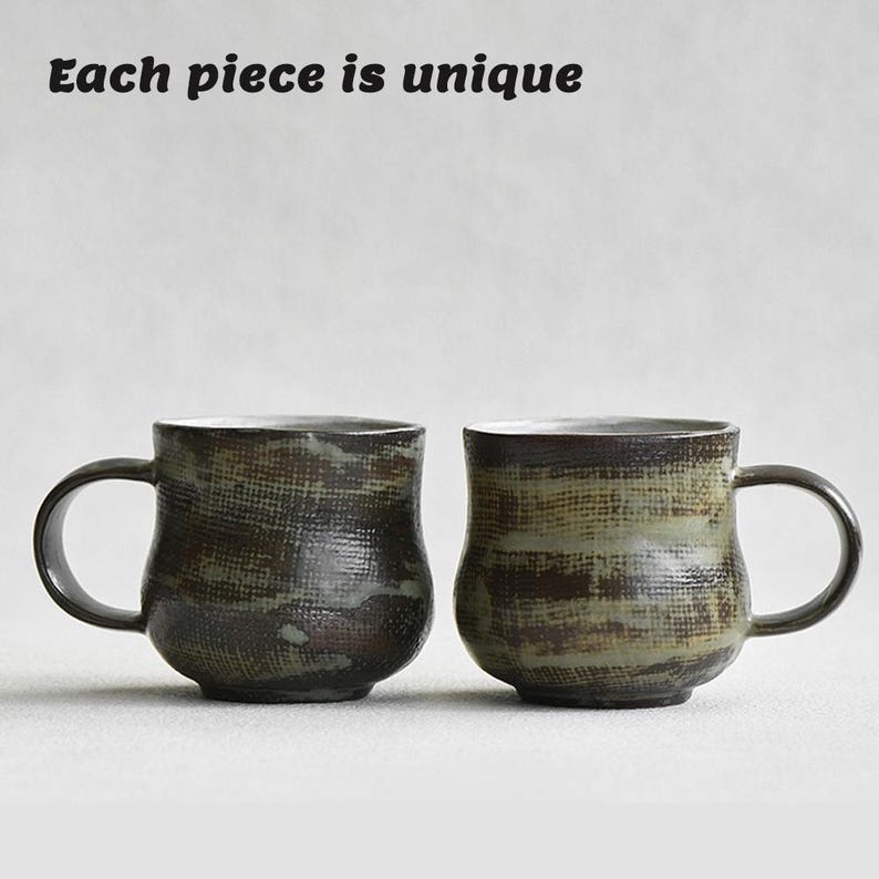 K&ouml;nnte beinhalten: Eine wei&szlig;e Keramik-Tasse mit schwarzem Henkel und dem Text "But First, Coffee" in schwarzer, fetter Schrift. Die Tasse steht auf einer Holzoberfl&auml;che. Die Tasse ist etwa 10 cm hoch.