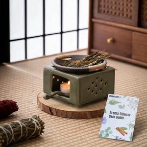 May include: A sage green ceramic oil burner with a square base, perforated sides, and a small handle. A brown ceramic dish with jute rope accents sits on top, holding dried herbs. A tea light candle glows inside, and a user guide is nearby.