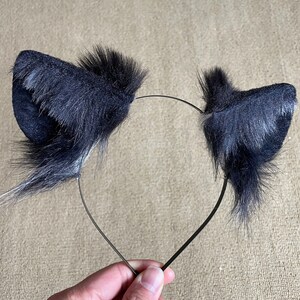 May include: Black furry cat ears headband. The headband is black and the ears are made of soft, fluffy black fur.