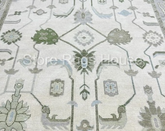 May include: A cream-colored rug with a traditional Persian design. The rug features a central medallion with intricate floral patterns in shades of green, blue, and gray.