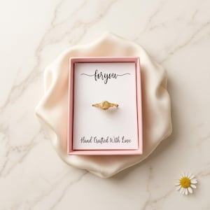 Gold initial signet ring with the letter A in a pink gift box on white satin cloth.