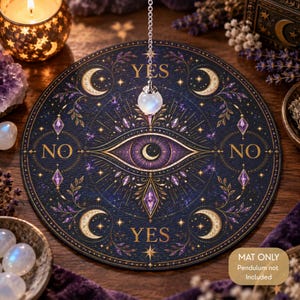 Peut inclure: Un tapis circulaire bleu foncé orné d'un motif d'œil central avec un croissant de lune, entouré d'étoiles dorées, de feuillages et des mots YES et NO imprimés en or. Une chaîne argentée avec un pendule en cristal clair est suspendue au-dessus.