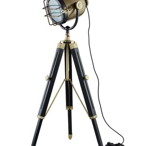 Può includere: Una lampada da terra a treppiede dorata e nera con una testa di faretto. La lampada ha un cavo nero e una spina nera.