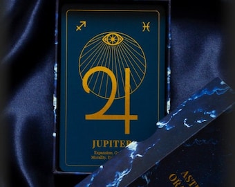 May include: A blue and gold oracle deck box with the text "Astrosoul Oracle Deck" and a card with the number "24" and the word "Jupiter" on it.