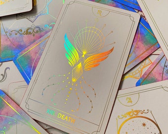 May include: A tarot card with a holographic finish depicting a phoenix with rainbow wings and the text "XIII. DEATH".