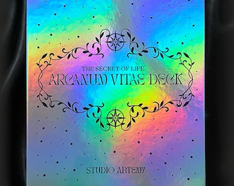 May include: A holographic box with a rainbow gradient background and black text that reads "The Secret of Life Arcanum Vitae Deck Studio Artemy".