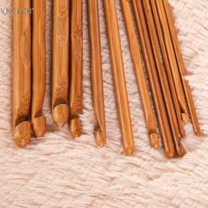 Peut inclure: Ensemble de crochets en bambou de différentes tailles, disposés en diagonale. Les crochets sont de couleur marron naturel et présentent une finition lisse. Le texte "VK TECH" est visible dans le coin supérieur gauche.