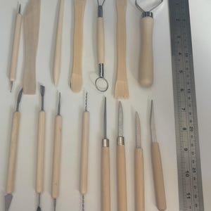 Pode incluir: Um conjunto de 14 ferramentas de escultura de madeira e metal para cer&acirc;mica, argila e artesanato. As ferramentas t&ecirc;m v&aacute;rias formas e tamanhos, incluindo uma ferramenta de la&ccedil;o, um raspador, uma ferramenta de costela e uma ferramenta de agulha.