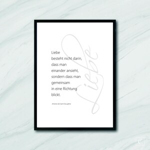 May include: A black and white printable quote about love, featuring the text "Liebe besteht nicht darin, dass man einander ansieht, sondern dass man gemeinsam in eine Richtung blickt." and the author's name "Antoine de Saint-Exupérie".