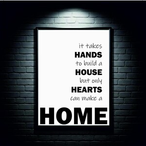 May include: A framed print with a black border against a dark brick wall. The print features the text: "it takes HANDS to build a HOUSE but only HEARTS can make a HOME."