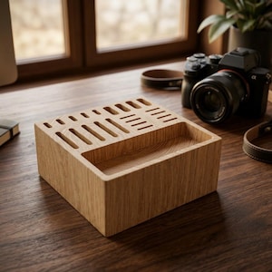 May include: A light brown wooden desk organiser featuring a rectangular tray section and multiple vertical slots of varying lengths and widths on the top surface, showcasing a natural wood grain texture throughout the entire block structure.