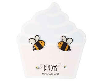 Könnte beinhalten: Ein Paar Bienen-Ohrstecker auf einer weißen, cupcakeförmigen Karte mit dem Text "Dindys Handmade in US".