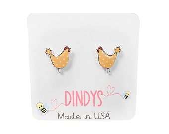 May include: A pair of yellow and white polka dot chicken stud earrings on a white card with the text "Dindys Made in USA" and a bee illustration.