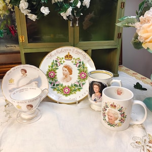 Op de afbeelding: Een verzameling herdenkingskeramiek met Queen Elizabeth II, bestaande uit een kop-en-schotelservies met de tekst St. Lawrence Seaway, een decoratief bord met een bloemenkrans en kroon, en twee witte mokken met portretten en bloemmotieven.