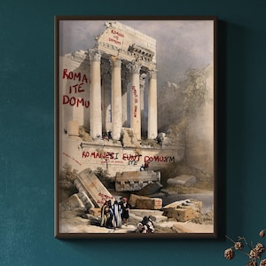 Könnte beinhalten: Gerahmter Druck einer klassischen Ruine mit großen weißen Säulen und roten Graffiti. Das Kunstwerk zeigt eine detaillierte Aquarellmalerei eines antiken Bauwerks mit Figuren in historischer Kleidung. Der Text auf dem Druck lautet "ROMA ITE DOMU" und "ROMANES IUNT DOMUSM ITE".