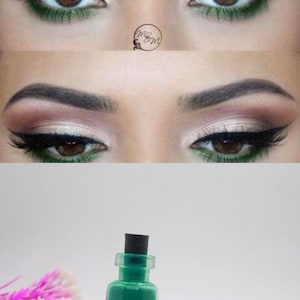 Könnte beinhalten: Eine kleine Glasflasche mit schwarzem Deckel, gefüllt mit grünem Glitter. Die Flasche steht auf einer weißen Oberfläche.