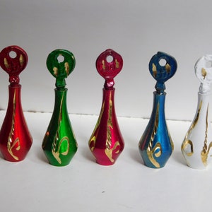 Pode incluir: Cinco frascos de perfume decorativos em vermelho, verde, rosa, azul e branco. Cada frasco tem formato de gota com detalhes dourados e uma tampa em forma de chave combinando. Os frascos estão dispostos em fila.