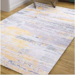 Könnte beinhalten: Ein abstrakter grauer und gelber Teppich mit Used-Look. Der Teppich hat ein modernes Design mit einem dezenten Muster.