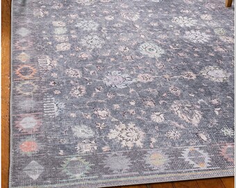 May include: A gray area rug with a floral pattern in shades of pink, blue, and green. The rug has a distressed look and a subtle sheen.