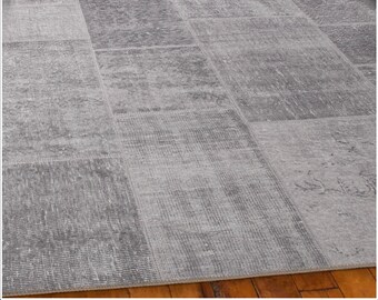 May include: A gray and white patchwork rug with a distressed look. The rug is made of different pieces of fabric sewn together, creating a unique and interesting design.
