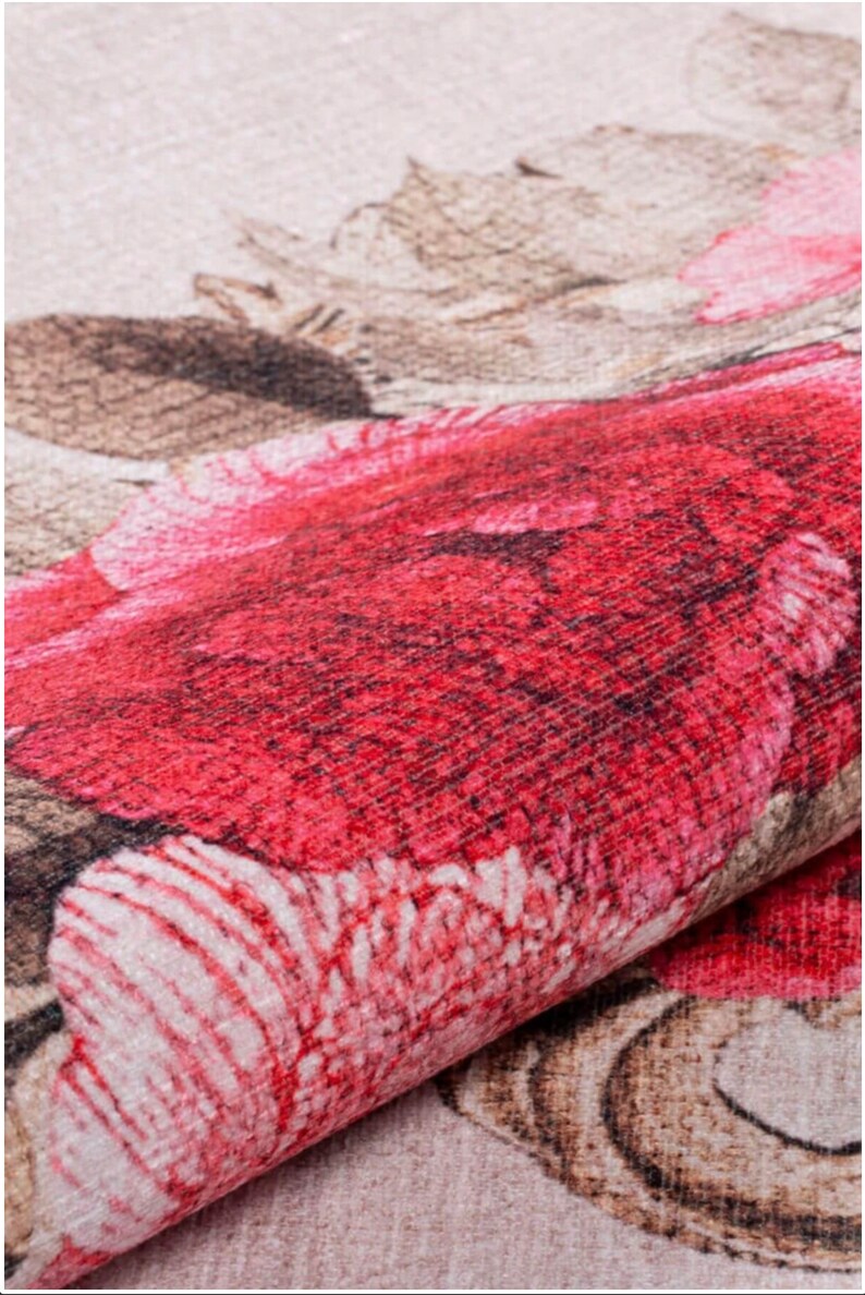 May include: Close-up of a red and pink floral patterned fabric. The fabric has a textured surface and a subtle sheen.