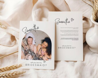 May include: A white card with a photo of two women in a bathroom with the text "Samantha" and "Will you be my bridesmaid?" printed on it.