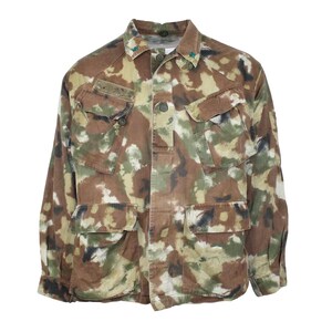May include: A camouflage jacket with a button-up front and multiple pockets. The jacket is in a brown, green, and white camouflage pattern.