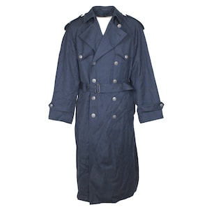 Può includere: Un trench coat blu navy con un design doppiopetto. Il cappotto presenta una cintura in vita, spalline sulle spalle e bottoni color argento. Il cappotto è realizzato in un tessuto strutturato e ha maniche lunghe.