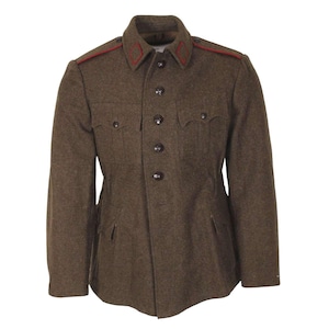 Puede incluir: Una chaqueta militar de lana marrón con ribetes rojos en el cuello y los hombros. La chaqueta tiene cierre de botones y dos bolsillos con solapa.