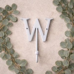 Könnte beinhalten: Eine weiße Keramik-Tasse mit schwarzem Henkel und dem Text "But First, Coffee" in handschriftlichem Stil. Die Tasse steht auf einer weißen Oberfläche. Die Tasse ist etwa 10 cm hoch.