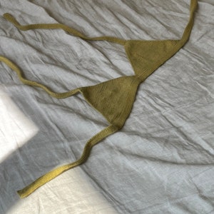 Puede incluir: Un top de bikini de triángulo de punto verde con tirantes finos.