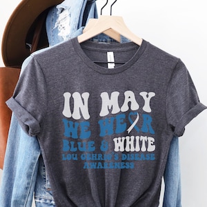 May include: Dark heather grey t-shirt with the text "In May We Wear Blue & White Lou Gehrig's Disease Awareness".