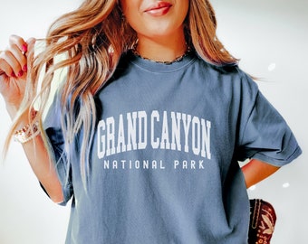 May include: A blue oversized t-shirt with white text that reads "GRAND CANYON NATIONAL PARK".