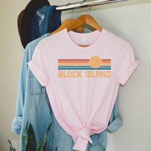 May include: Pink t-shirt with a retro sunset graphic and the text "BLOCK ISLAND" in a vintage font.