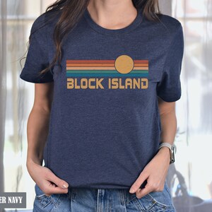 May include: A heather navy blue t-shirt with a retro-style graphic of a sunset over a beach with the text "BLOCK ISLAND" in white.