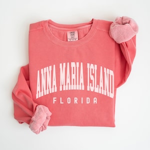 May include: A coral pink sweatshirt with white text that reads "Anna Maria Island, Florida".