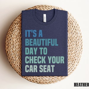 May include: Heather navy blue t-shirt with the text "It's a beautiful day to check your car seat" in a gradient of blue and green.