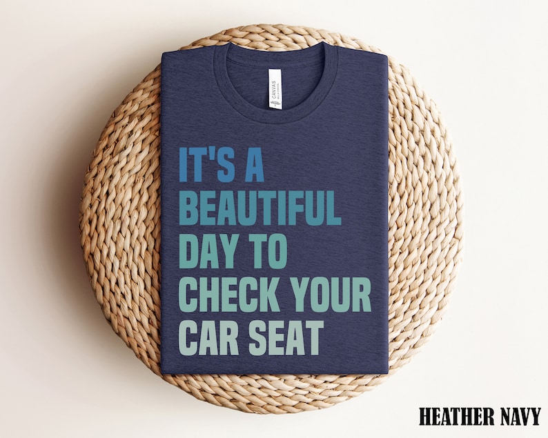 May include: Heather navy blue t-shirt with the text "It's a beautiful day to check your car seat" in a gradient of blue and green.