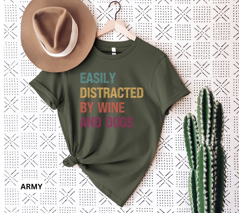 May include: A green t-shirt with the text "EASILY DISTRACTED BY WINE AND DOGS" in a vintage style font. The text is in different colors, including yellow, orange, red, and purple.