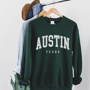 May include: A dark green sweatshirt with the text "AUSTIN TEXAS" in white lettering.
