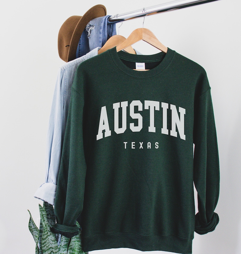 May include: A dark green sweatshirt with the text "AUSTIN TEXAS" in white lettering.