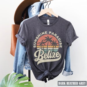 May include: Dark heather grey t-shirt with a vintage-style graphic of palm trees and a sunset. The graphic says "Sunshine Paradise Belize".