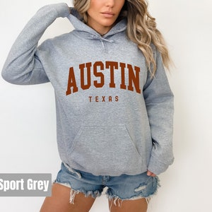 May include: A gray hooded sweatshirt with the text "AUSTIN TEXAS" in brown lettering.