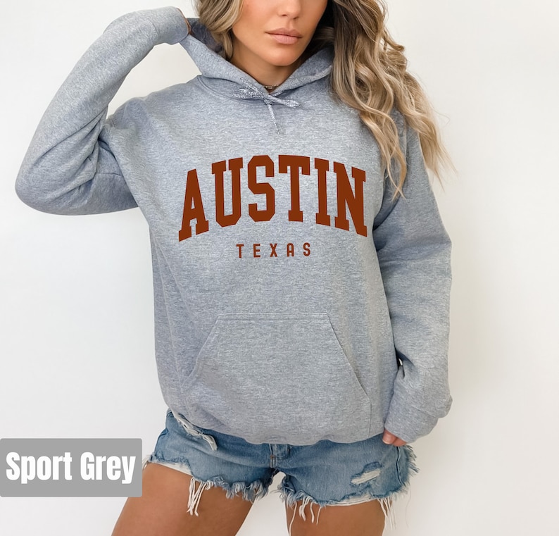 May include: A gray hooded sweatshirt with the text "AUSTIN TEXAS" in brown lettering.