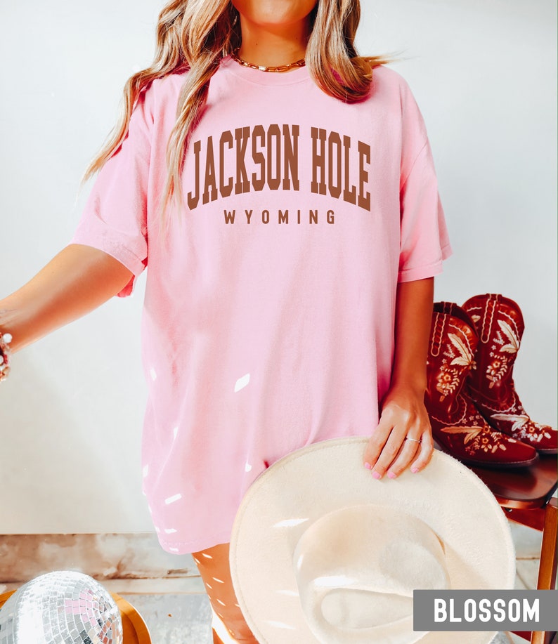 May include: A pink t-shirt with the text "JACKSON HOLE WYOMING" in brown letters.