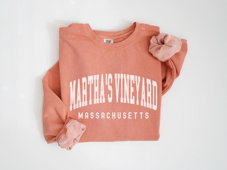 May include: A coral colored sweatshirt with the text "Martha's Vineyard Massachusetts" in white.