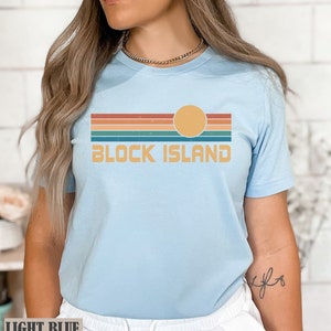 May include: A light blue t-shirt with a retro sunset graphic and the text "BLOCK ISLAND" in white.