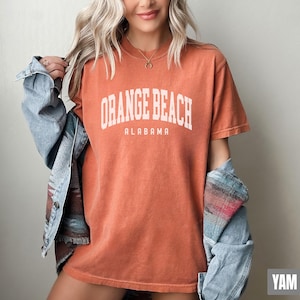 Puede incluir: Una camiseta naranja quemada con el texto "Orange Beach Alabama" en blanco.