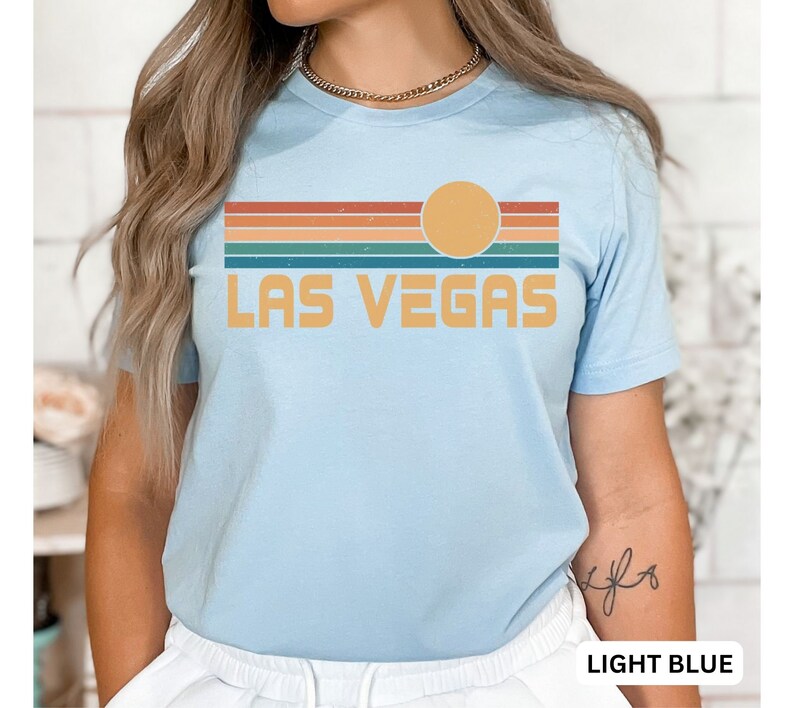 May include: Light blue t-shirt with a retro sunset graphic and the text "LAS VEGAS" in yellow.